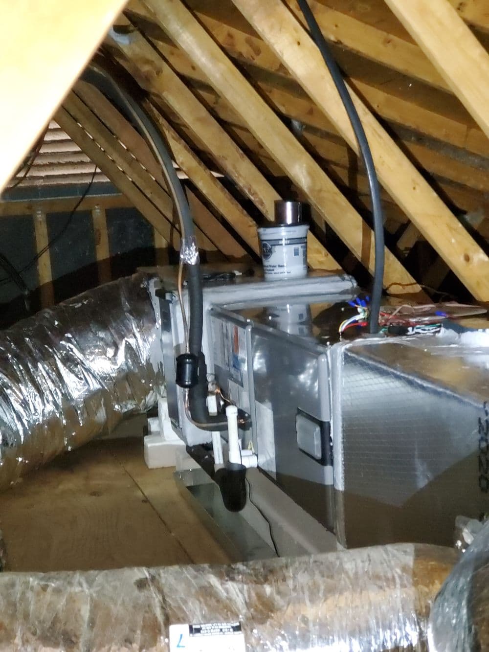 HVAC system installed in attic with ductwork and insulation visible.