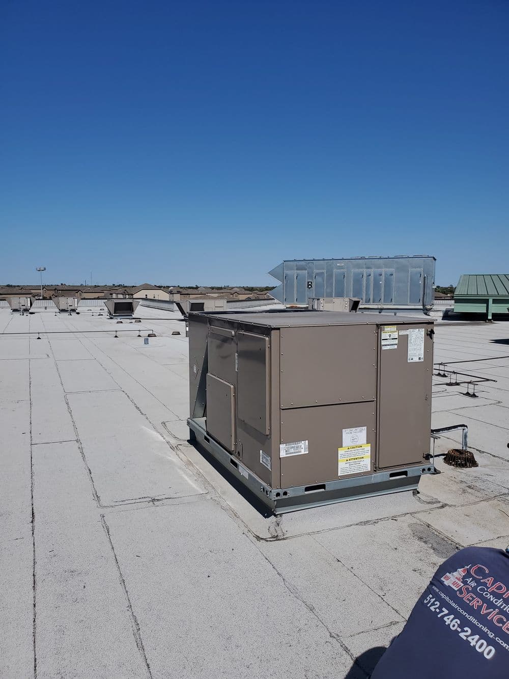 Roof-mounted HVAC unit on a commercial building with clear blue sky background.