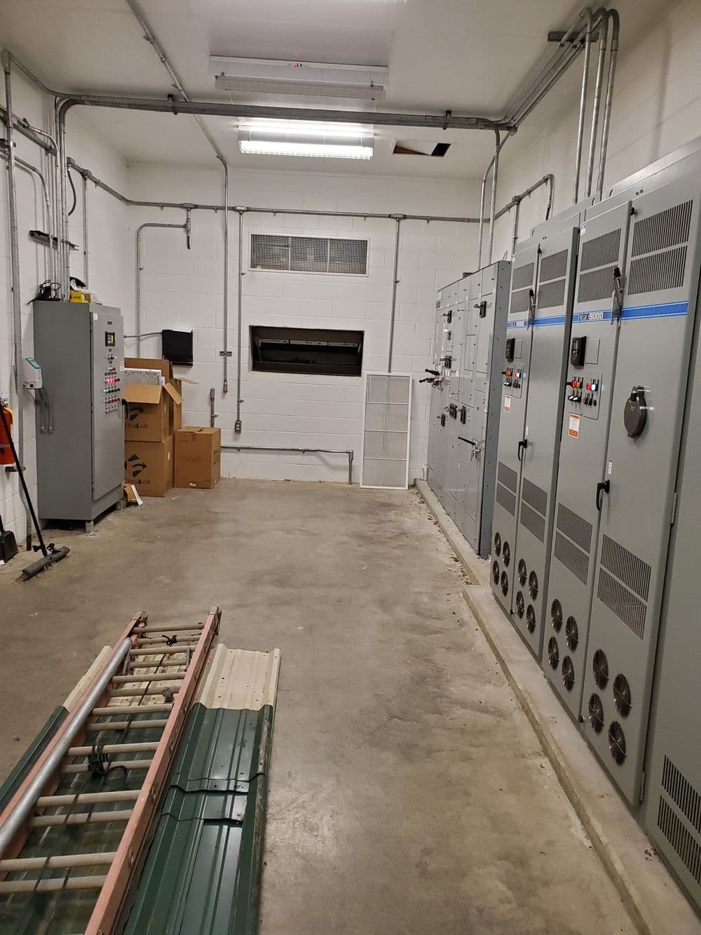 Electrical maintenance room with control panels, tools, and a concrete floor.